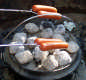 View - The hot dogs cook over the coals on the dutch oven